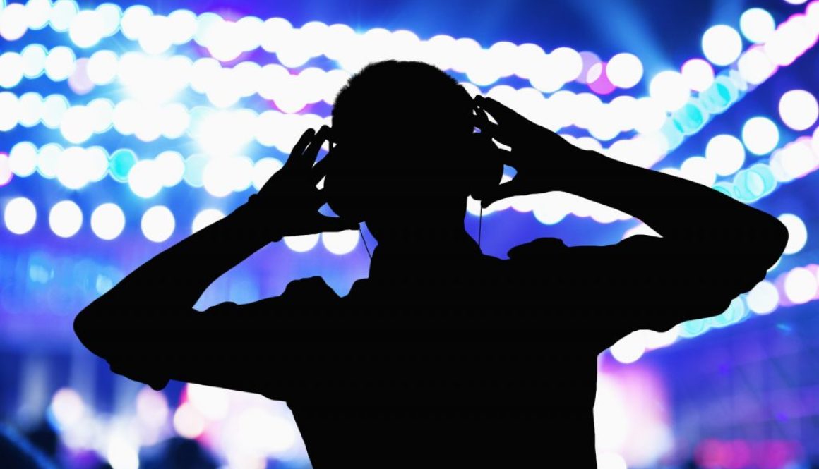silhouette-of-dj-wearing-headphones-and-performing-at-a-night-club